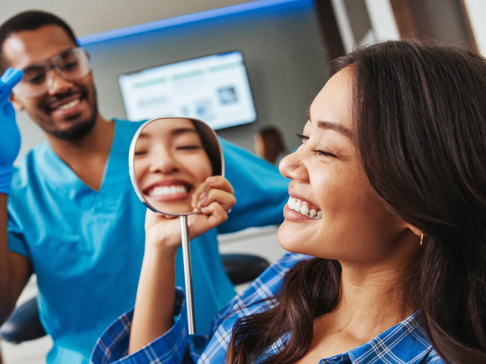 A woman admiring her smile in a mirror at the dentist