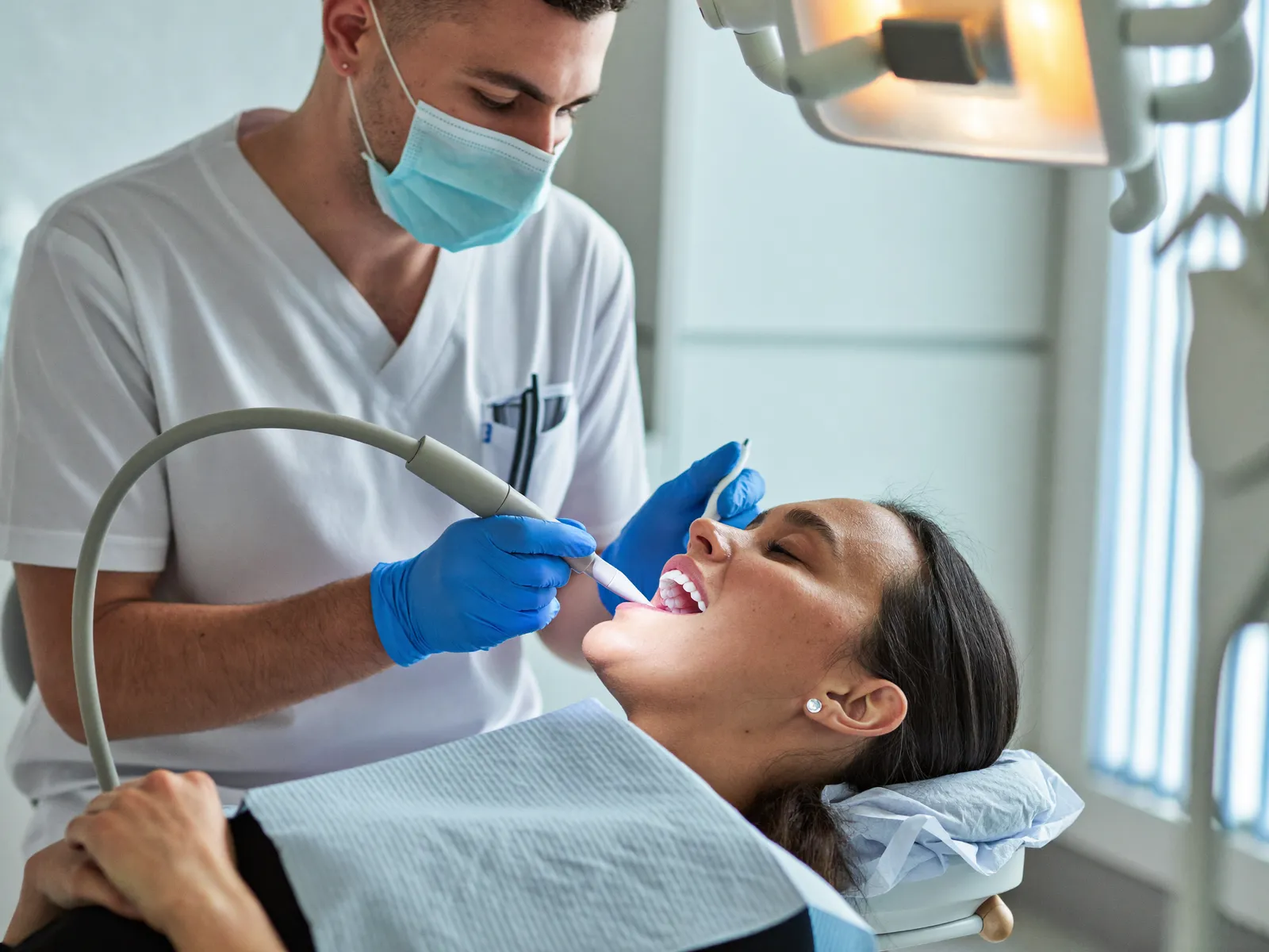 A hygienist performing a professional cleaning in a bright operatory