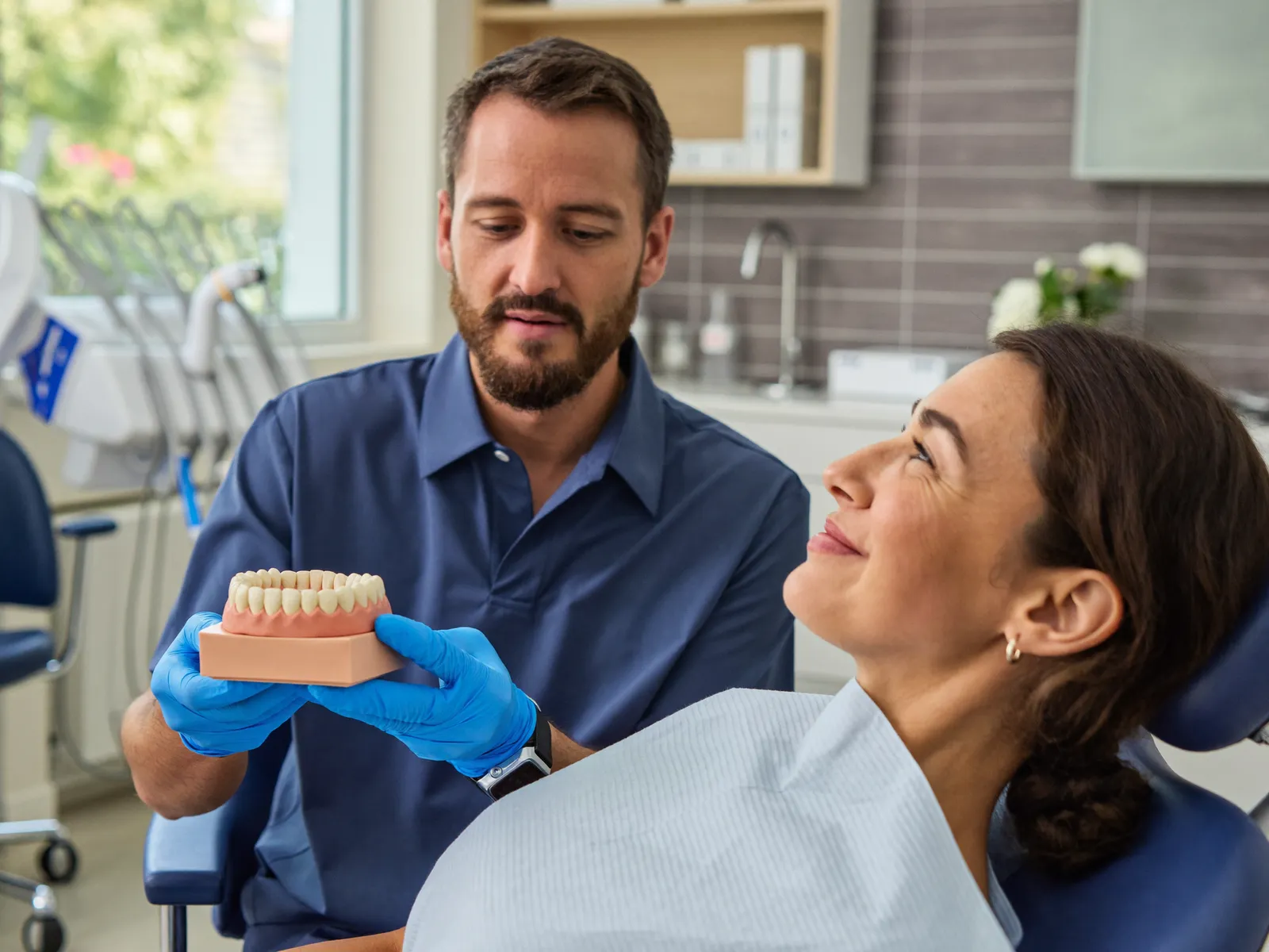 A dentist explaining care using a tooth model