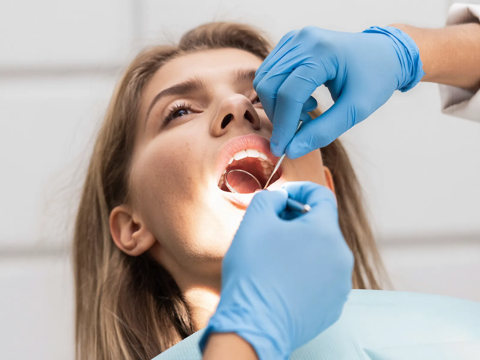 A dentist examining a patient’s tooth with a dental mirror