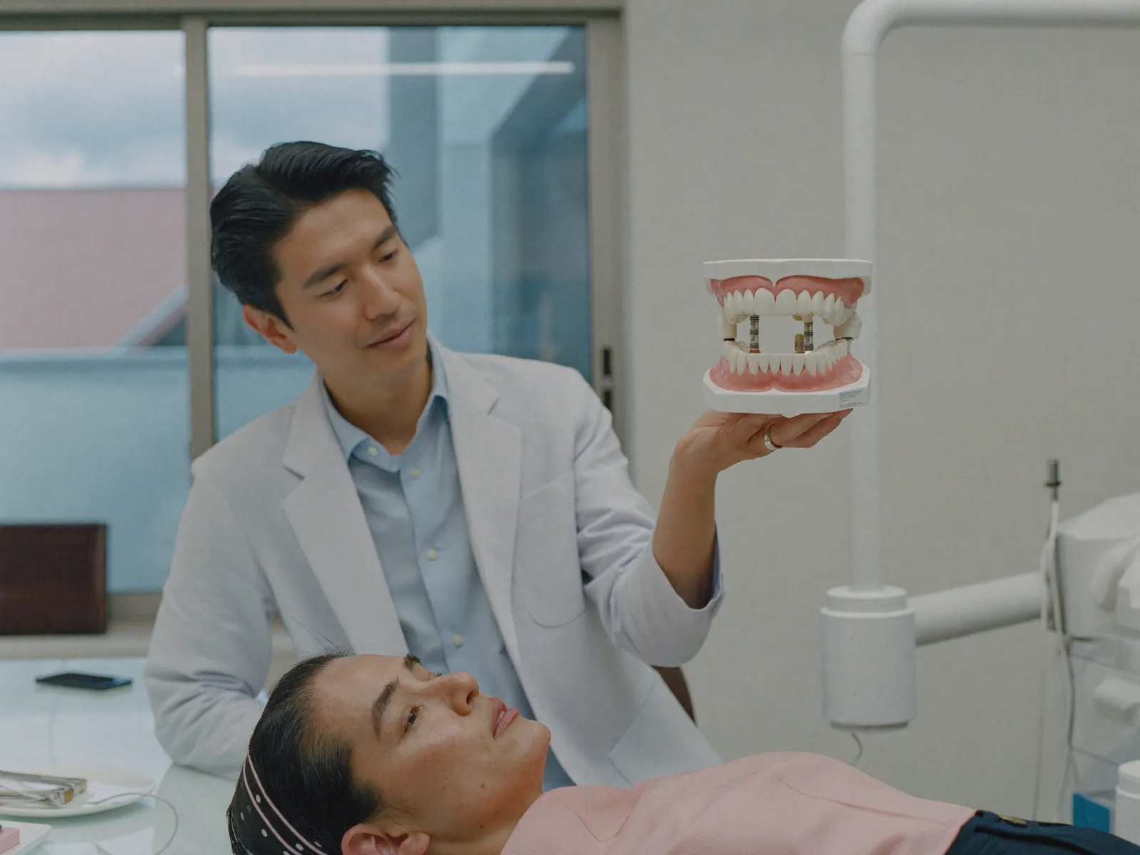 A dentist explaining a dental implant model to a patient