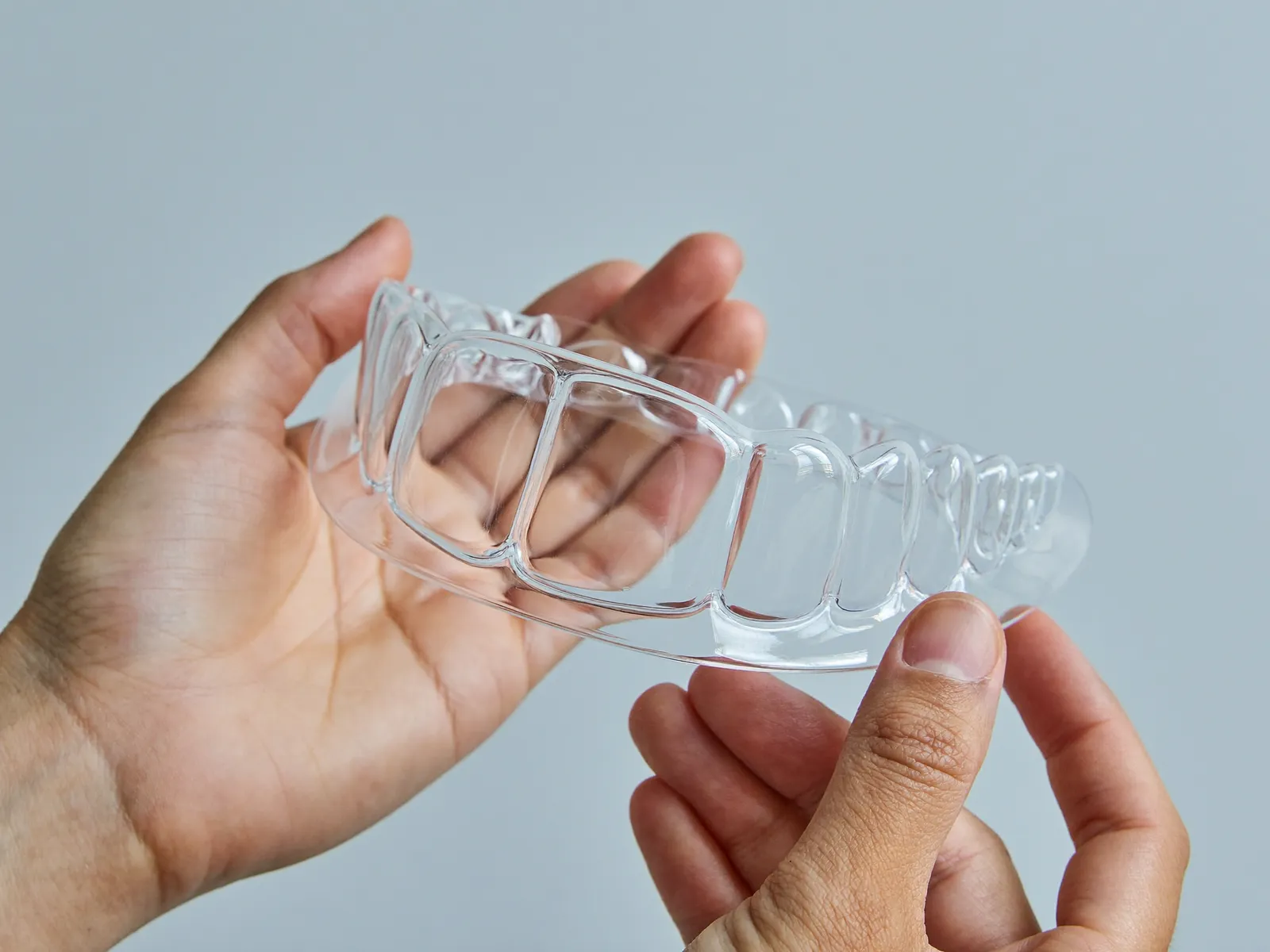 Hands holding a clear custom dental mouthguard