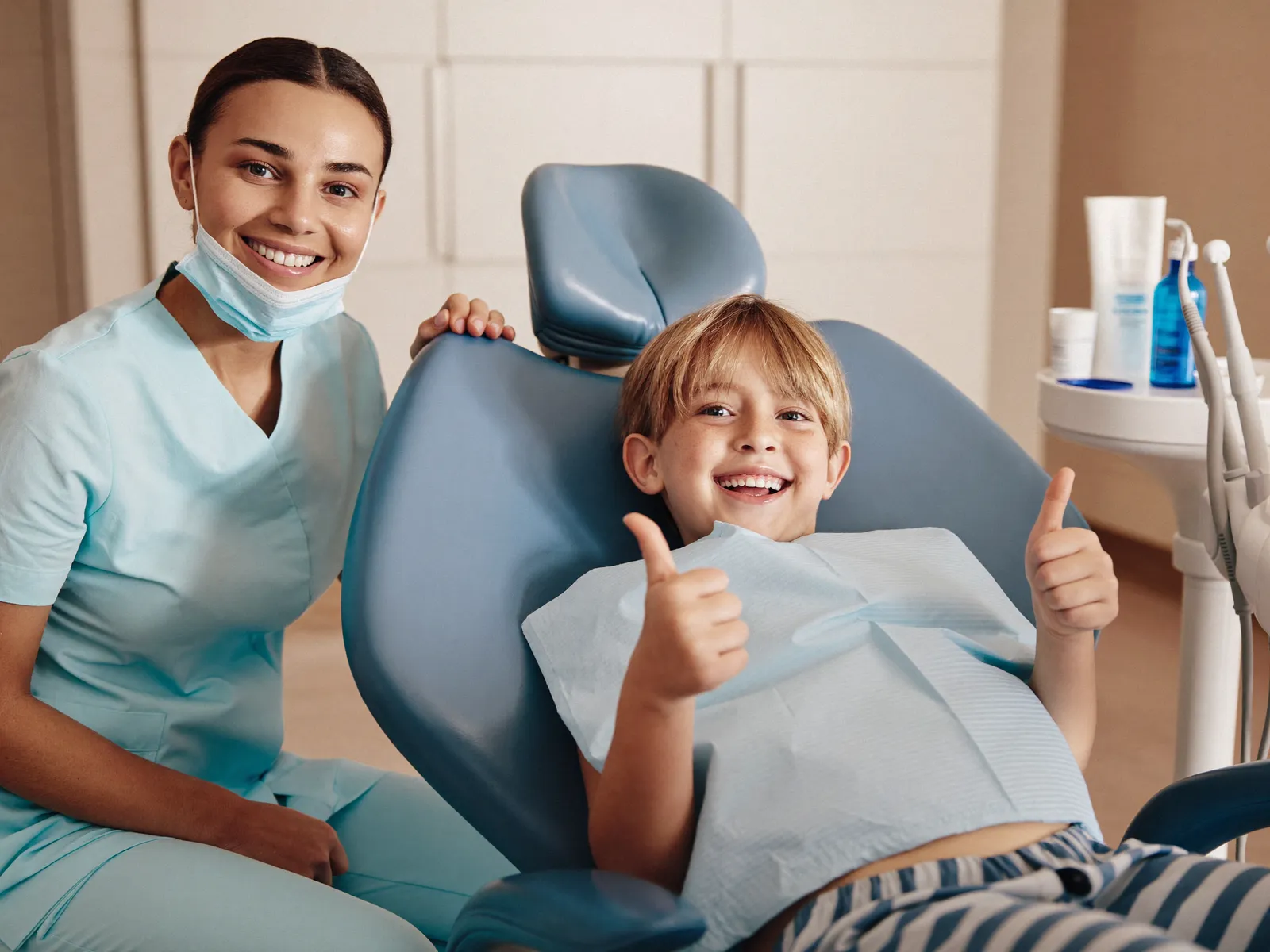 A happy child giving a thumbs up in a dental chair